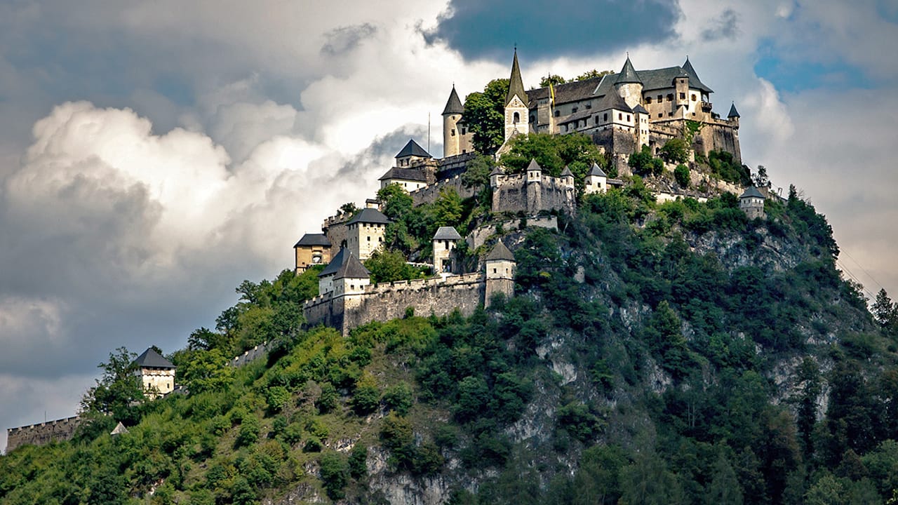 Hochosterwitz Castle crowning a steep forested hill beneath dramatic clouds in Carinthia, Austria.