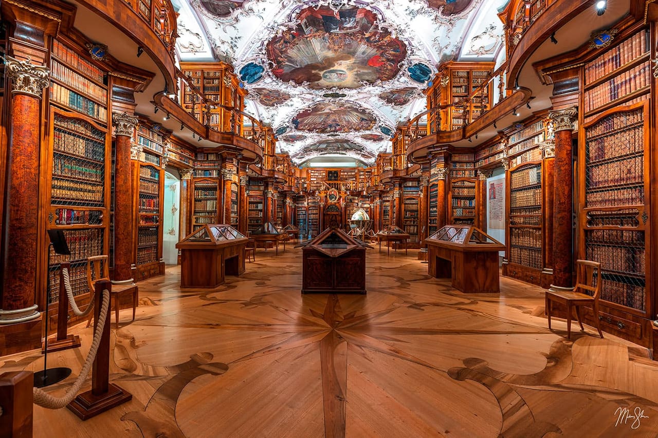 Abbey Library of Saint Gall in Switzerland featuring ornate woodwork, ceiling frescoes, and historic books.