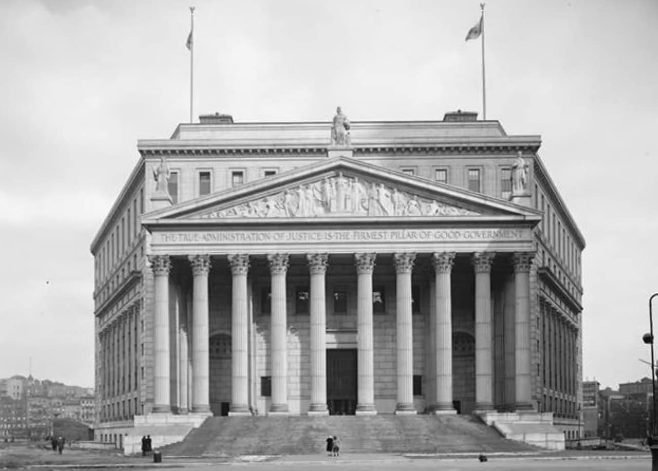 New York County Courthouse with towering columns, broad stone steps, and a sculpted classical pediment.