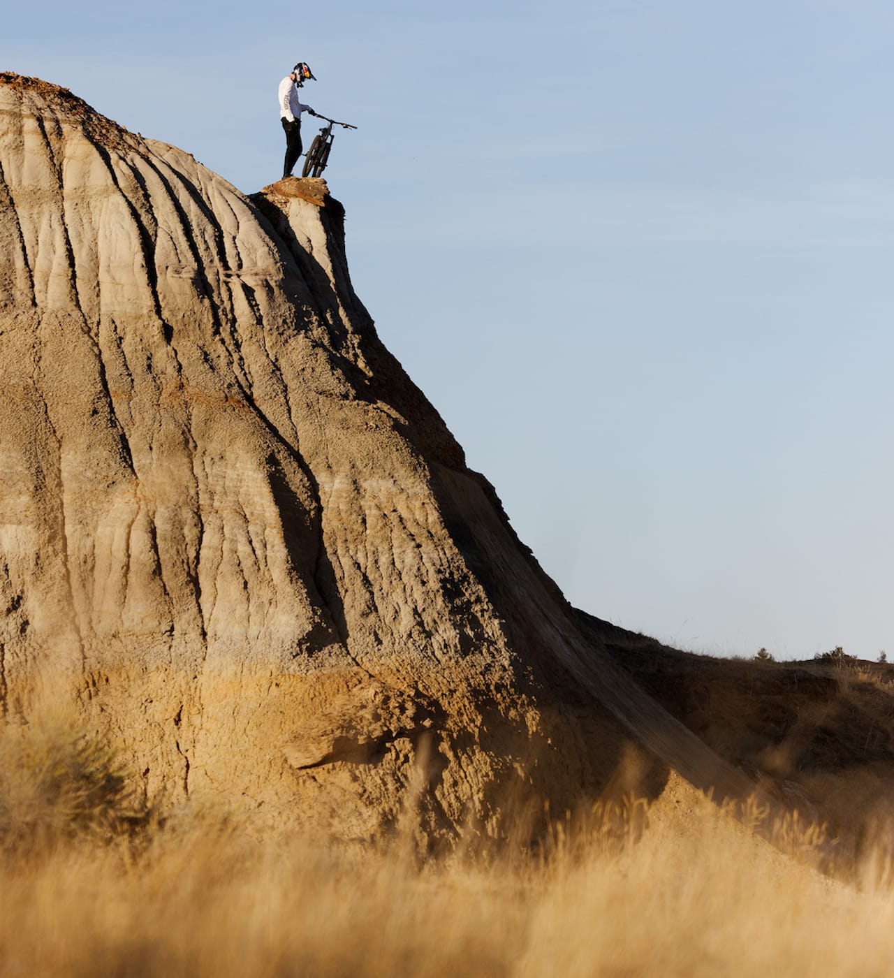 A mountain biker shown holding his bike at the top of a very steep bluff.