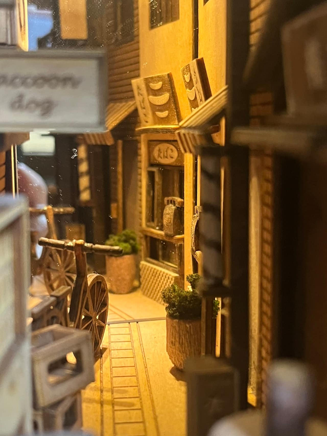 Image of a bookshelf insert showing a narrow Japanese alley with shops and 2 bicycles.