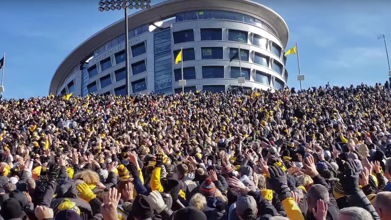 Enthusiastic fans gather to wave at the hospital, embodying the spirit of the Hawkeye Wave and inspiring young patients.