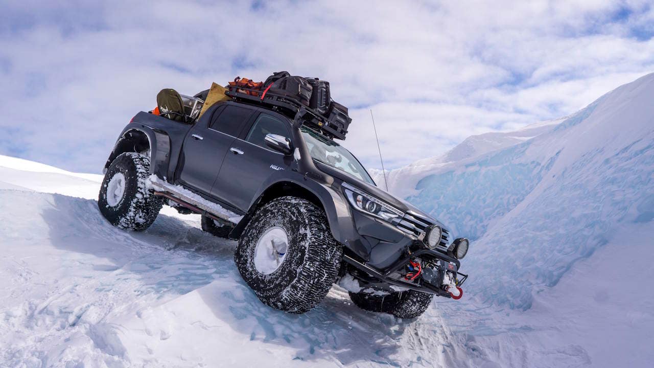 Black Toyota Hilux four door truck with 44 inch tires parked on steep ice in the Arctic.