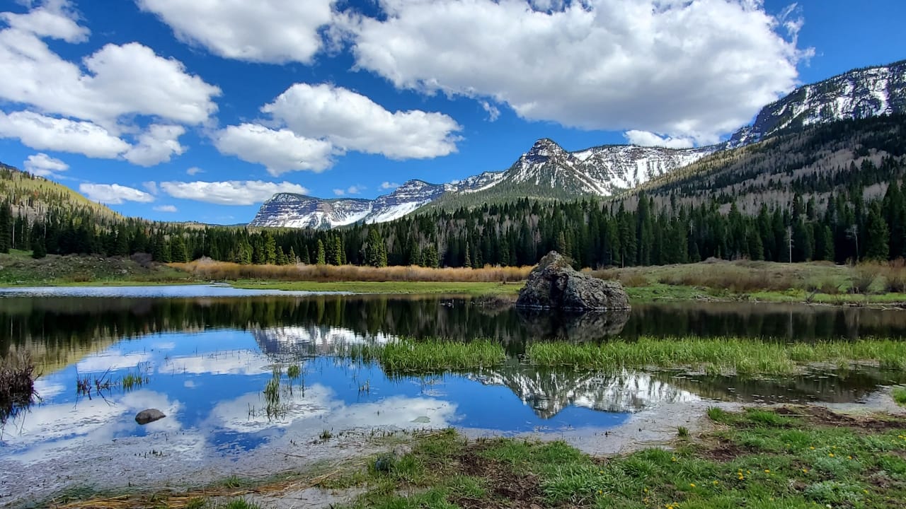 A picturesque lake surrounded by the majestic Flat Tops mountains and lush trees in the Flat Tops Wilderness area.