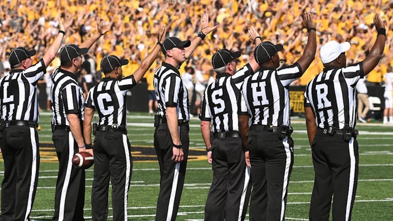 Officials wave during the Hawkeye Wave, uniting with 70,000 fans in a powerful show of support for pediatric patients.