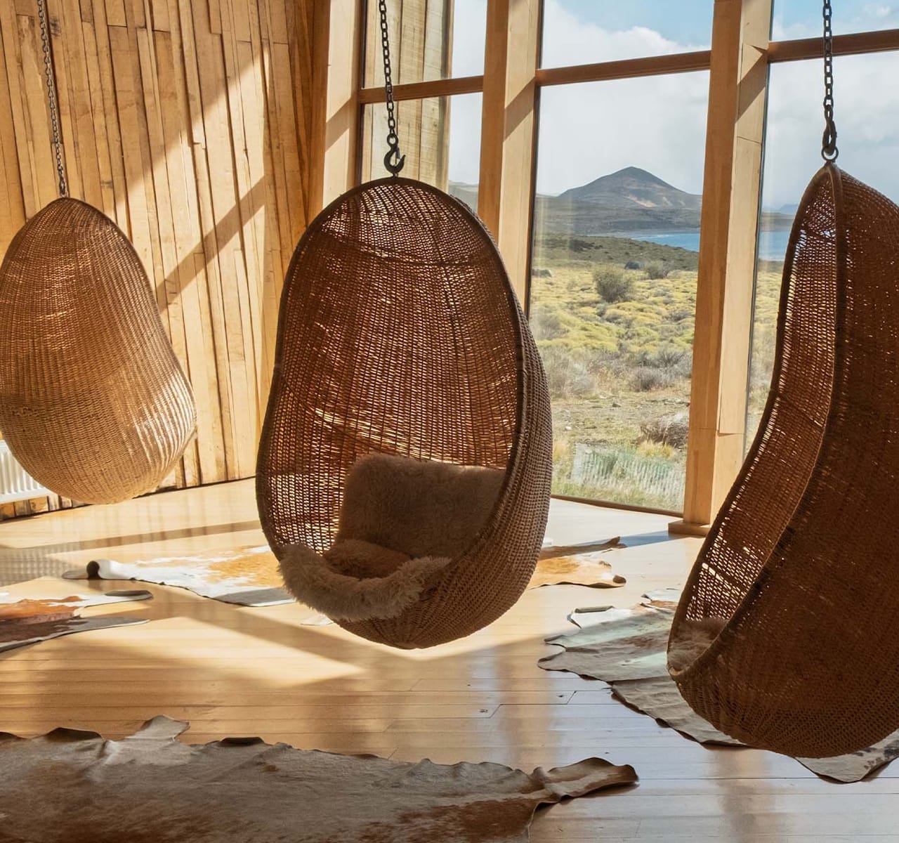 A tranquil area in Tierra Patagonia Hotel, adorned with hanging chairs and hide rugs, ideal for peaceful moments.