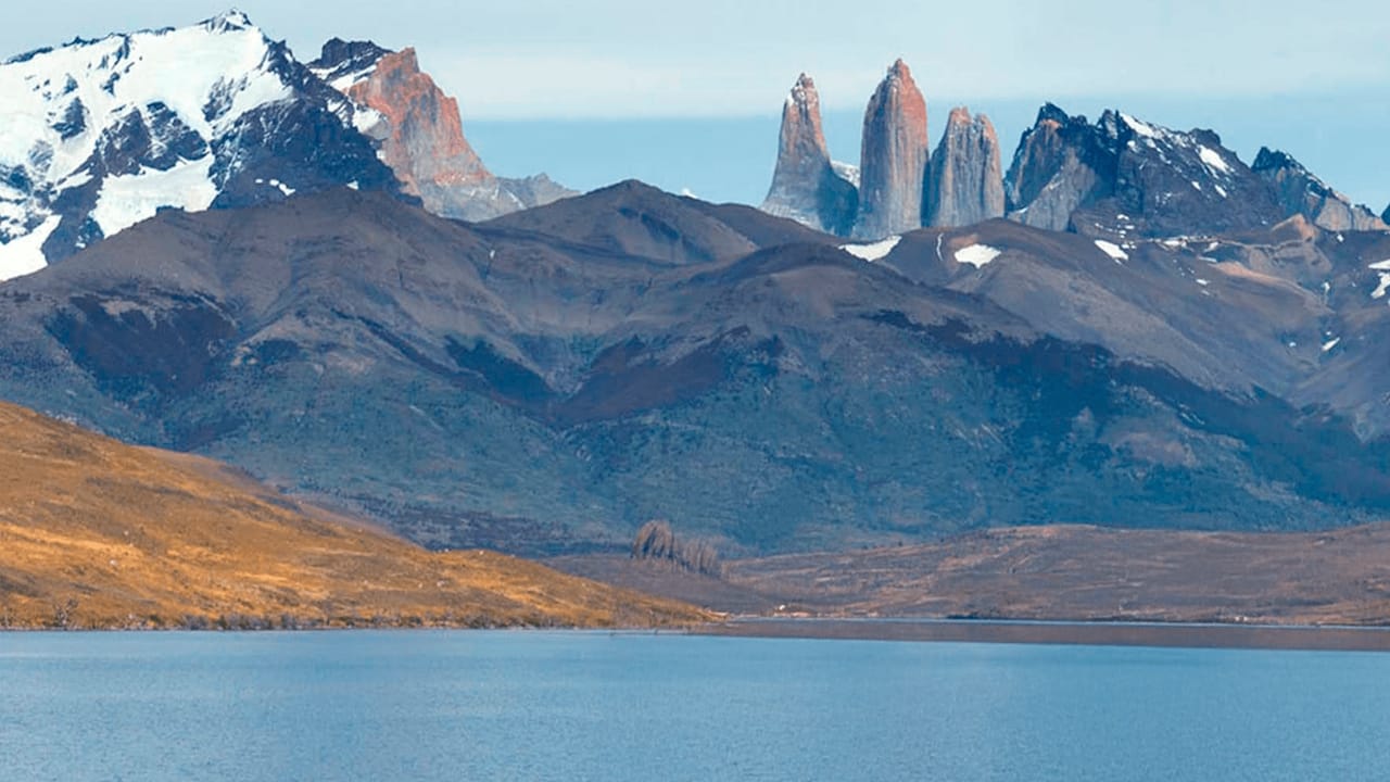 A stunning view of Laguna Azul, a large body of water with the majestic peaks of Torres del Paine in the background.