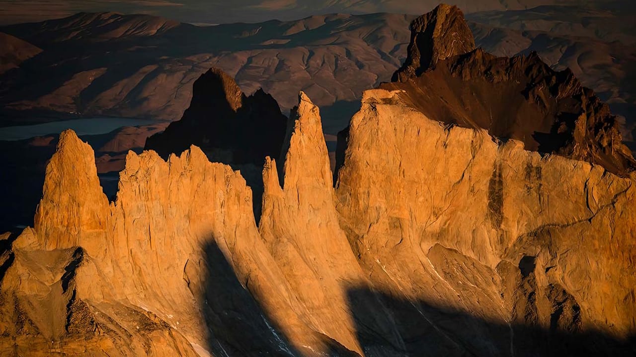 A breathtaking sunset illuminates the Torres del Paine mountains, creating a stunning silhouette against the vibrant sky.