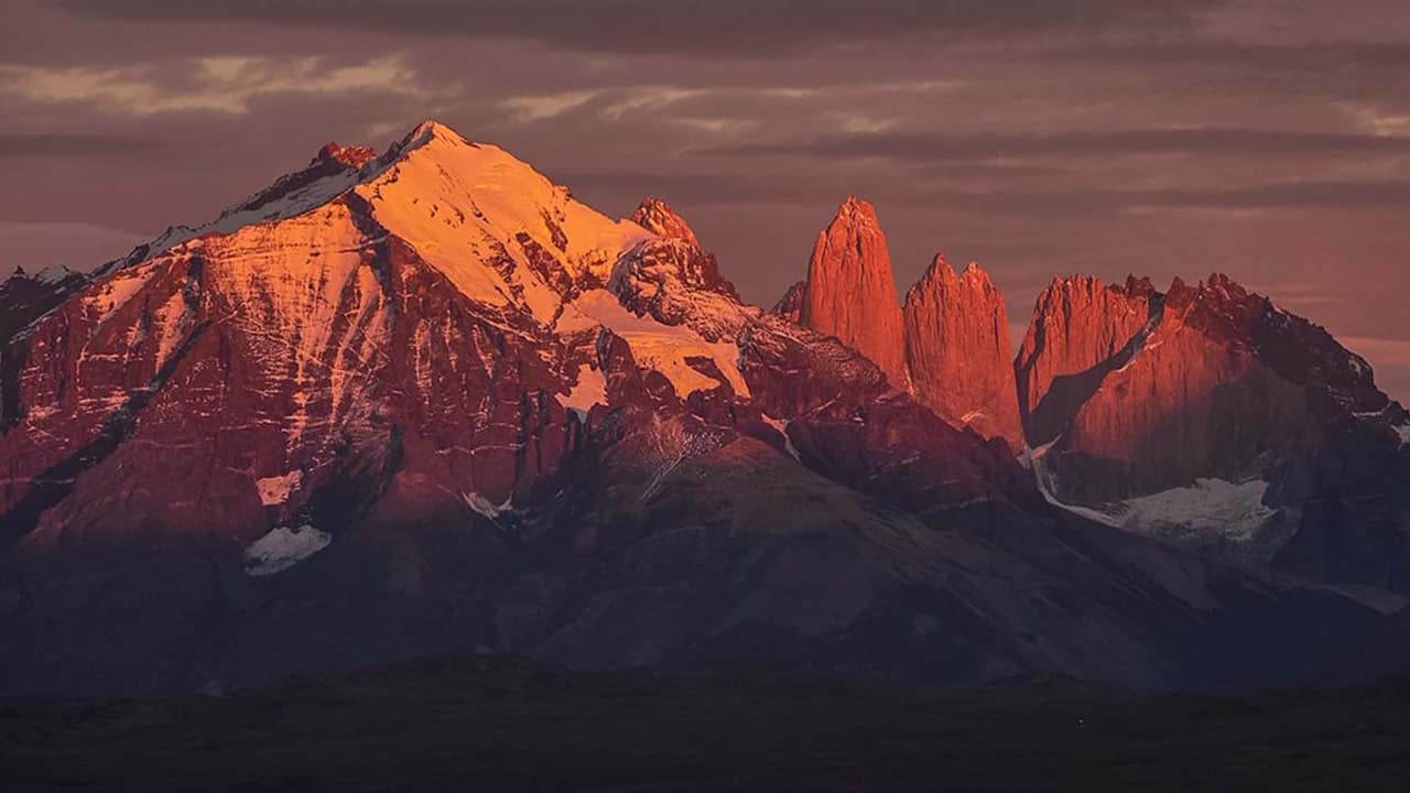 A breathtaking sunset casts vibrant colors over the majestic Torres del Paine mountains in Patagonia.