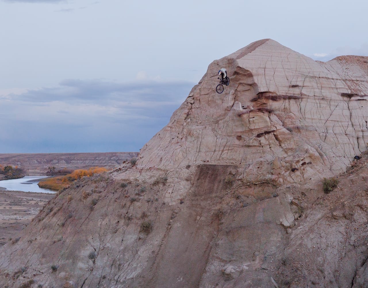  Brandon Semenuk jumps his mountain bike off of a peaked ridge hill onto a steep landing ramp.