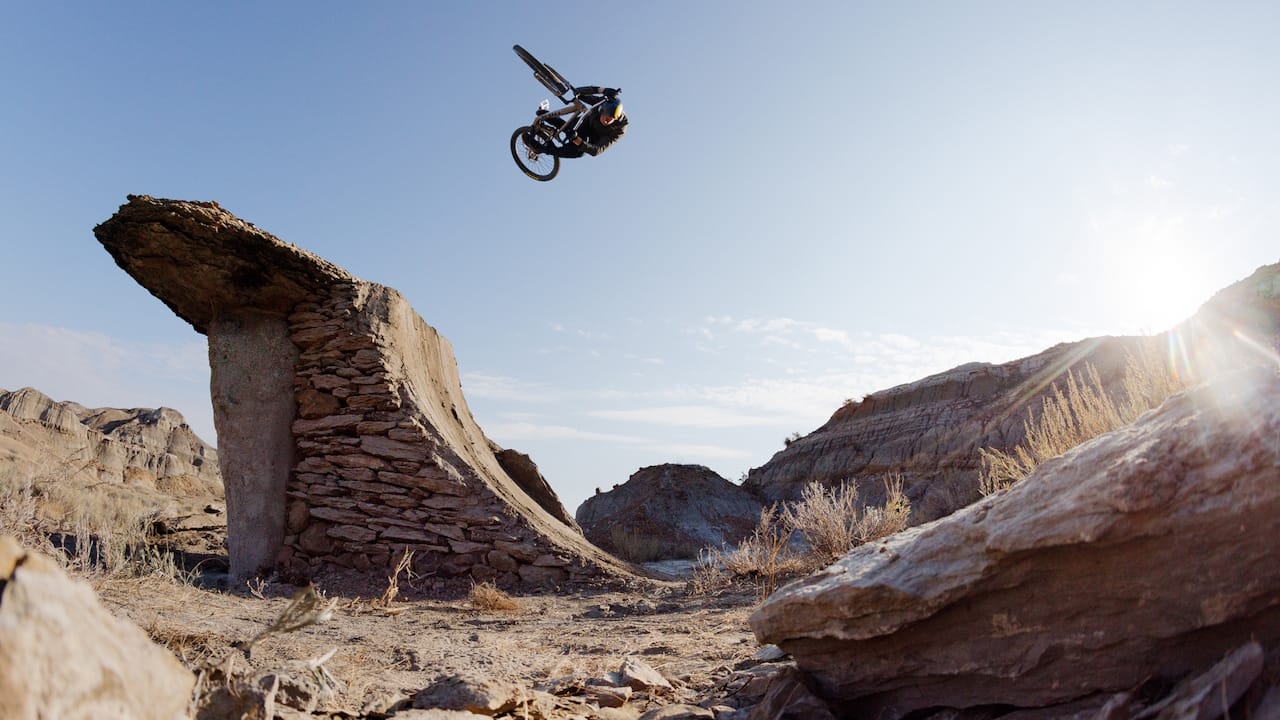 A mountain biker jumping his mountain bike against a blue sky.