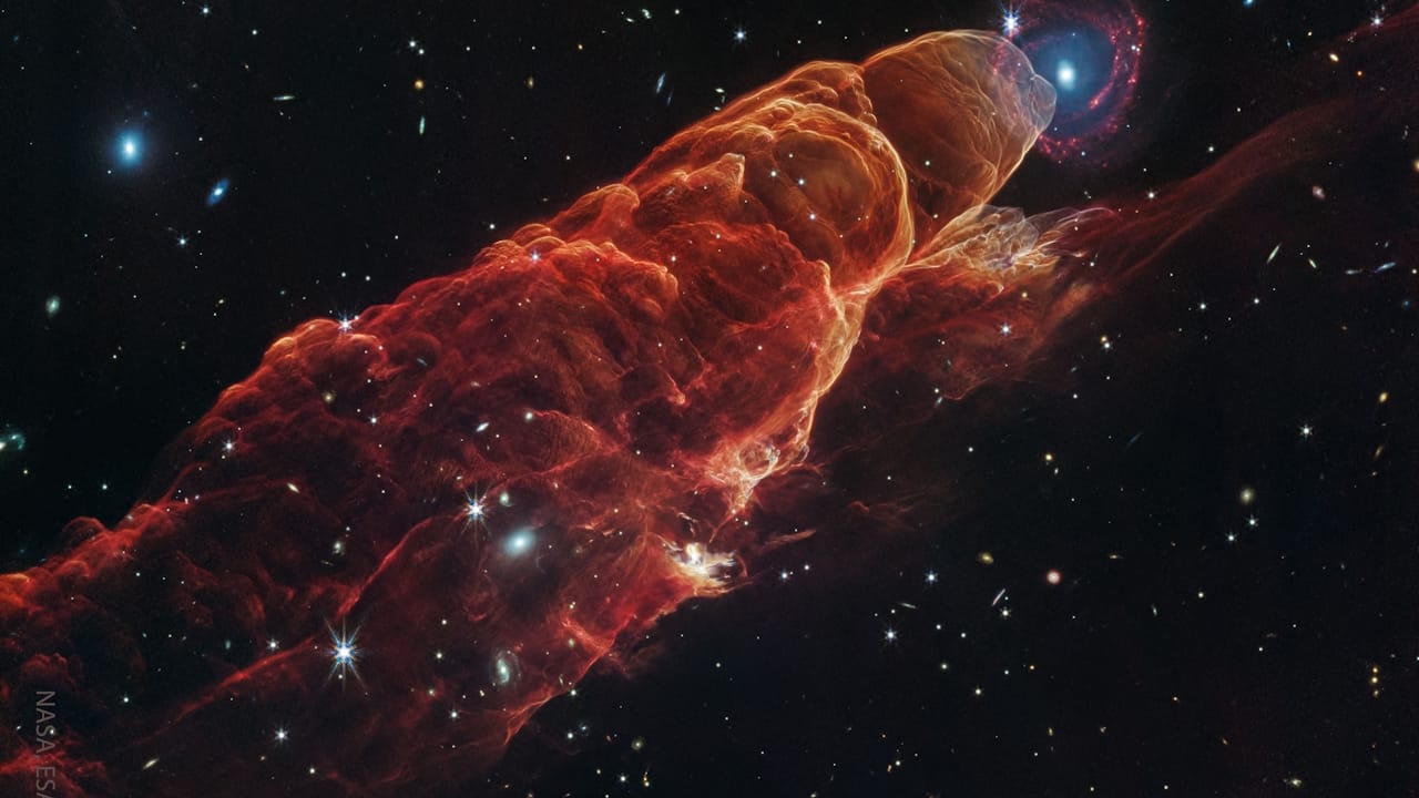 NASA space pictures. Infrared image of Herbig-Haro 49, revealing a distant spiral galaxy surrounded by glowing shock waves.