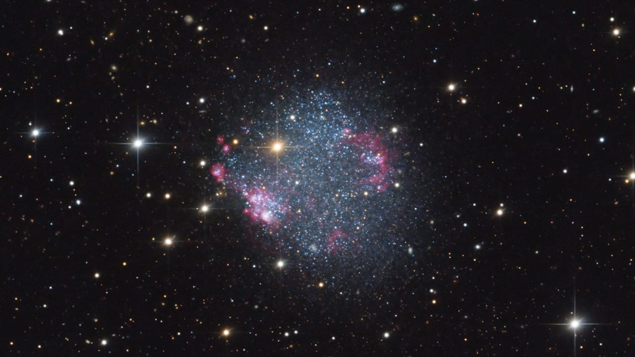 A brilliant blue star twinkles in the sky, showcasing the star-forming regions of the small galaxy Sextans A.