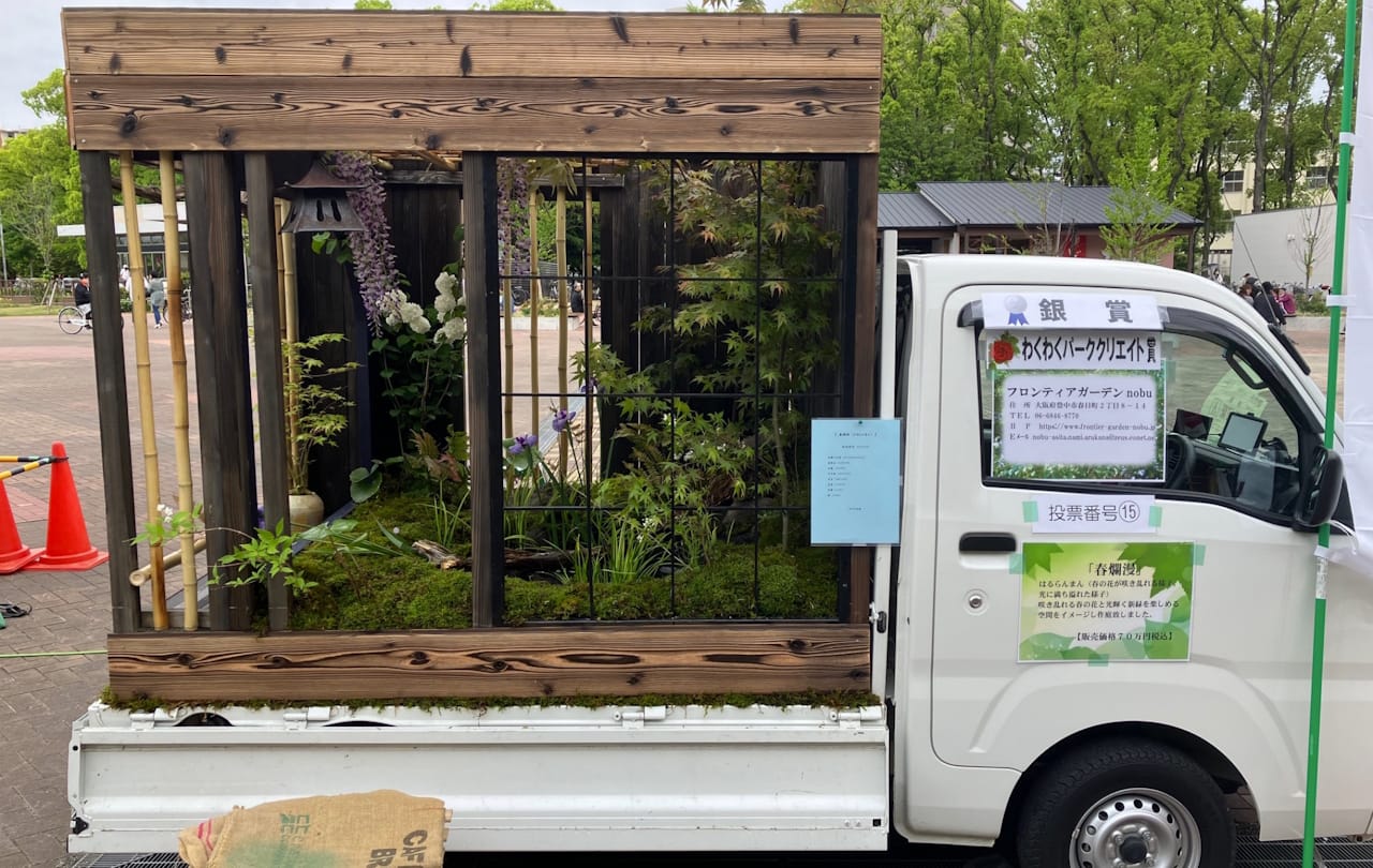 A bamboo and wood structure enclosing a garden rising out of the bed of a small truck.