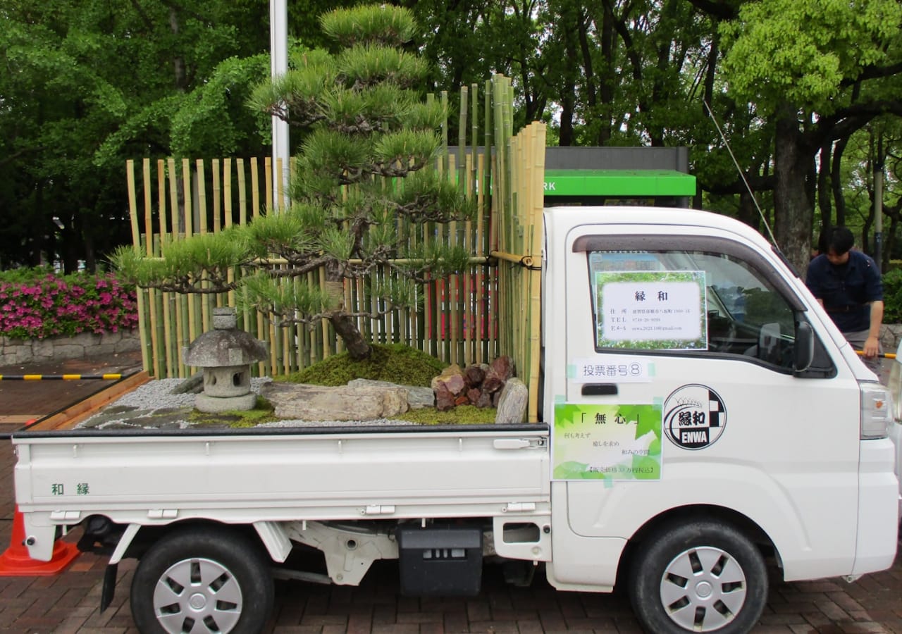 A Zen garden with a Zen lantern and a large evergreen plant in the back of a small truck.