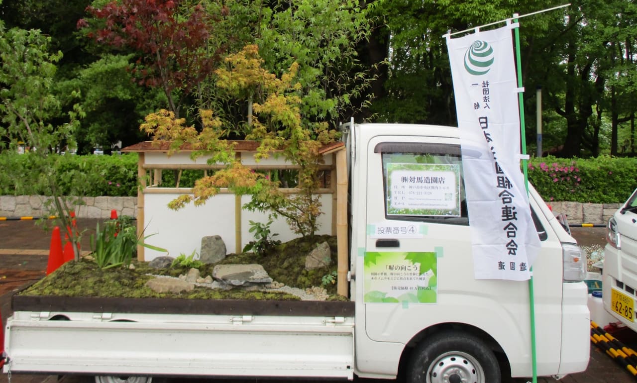 A garden with a white rock stream and a Japanese Maple in the back of a small truck.