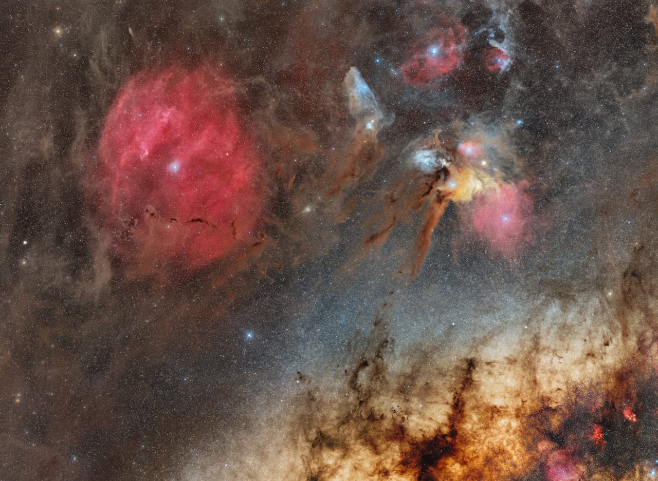 A vibrant nebula showcases red and blue stars, with the Milky Way and Zeta Ophiuchi, captured in a breathtaking night sky.