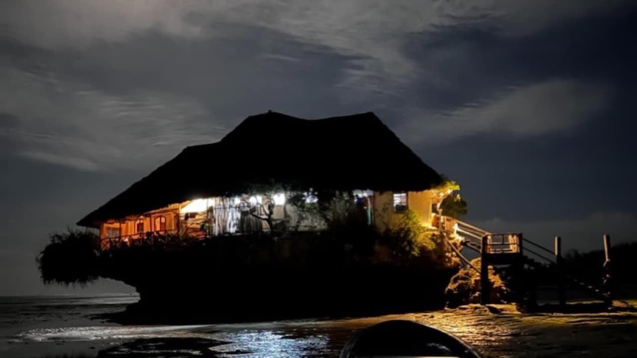 Lit up night time view of The Rock with bright moonlight showing through the clouds.