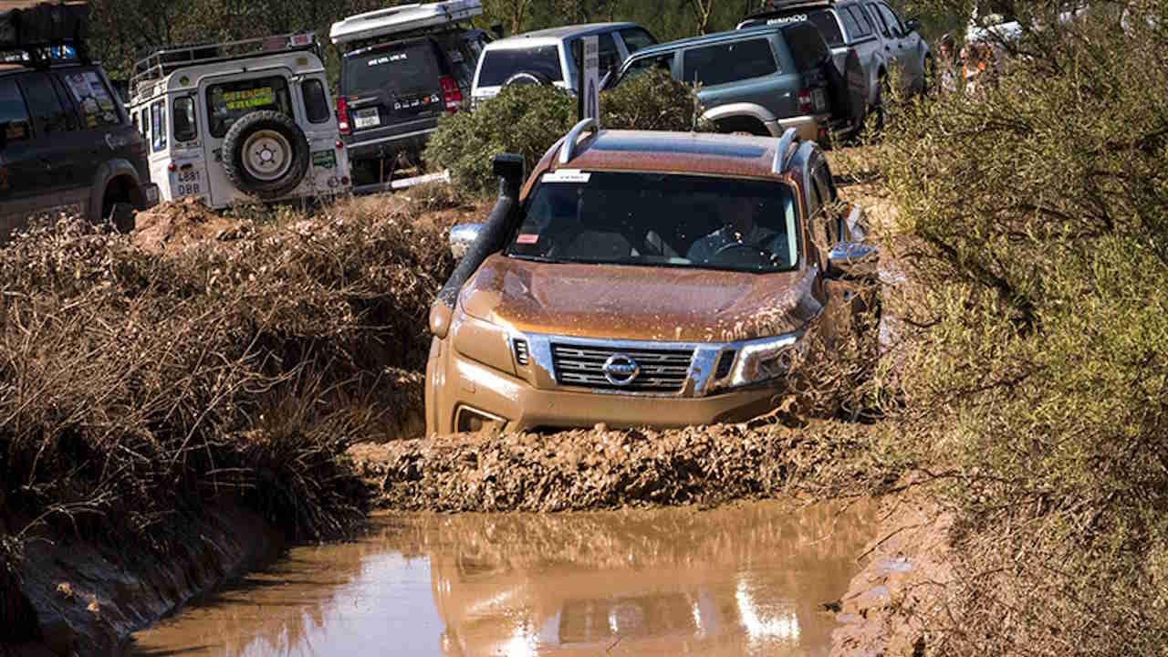 Brown Nissan Navara driving into deep muddy water as part of a 4x4 challenge course.
