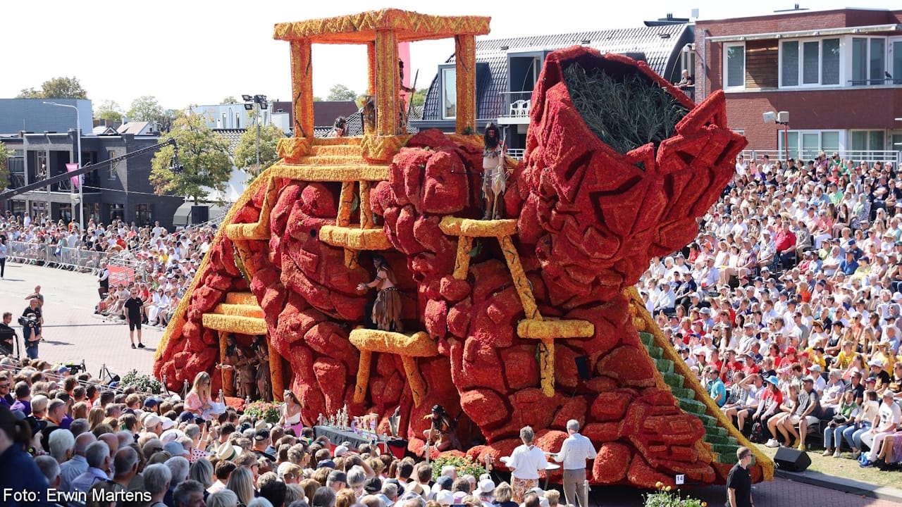 Red and gold flower parade float depicting a sculpture of the Mayan god Chaac at the top of a temple.