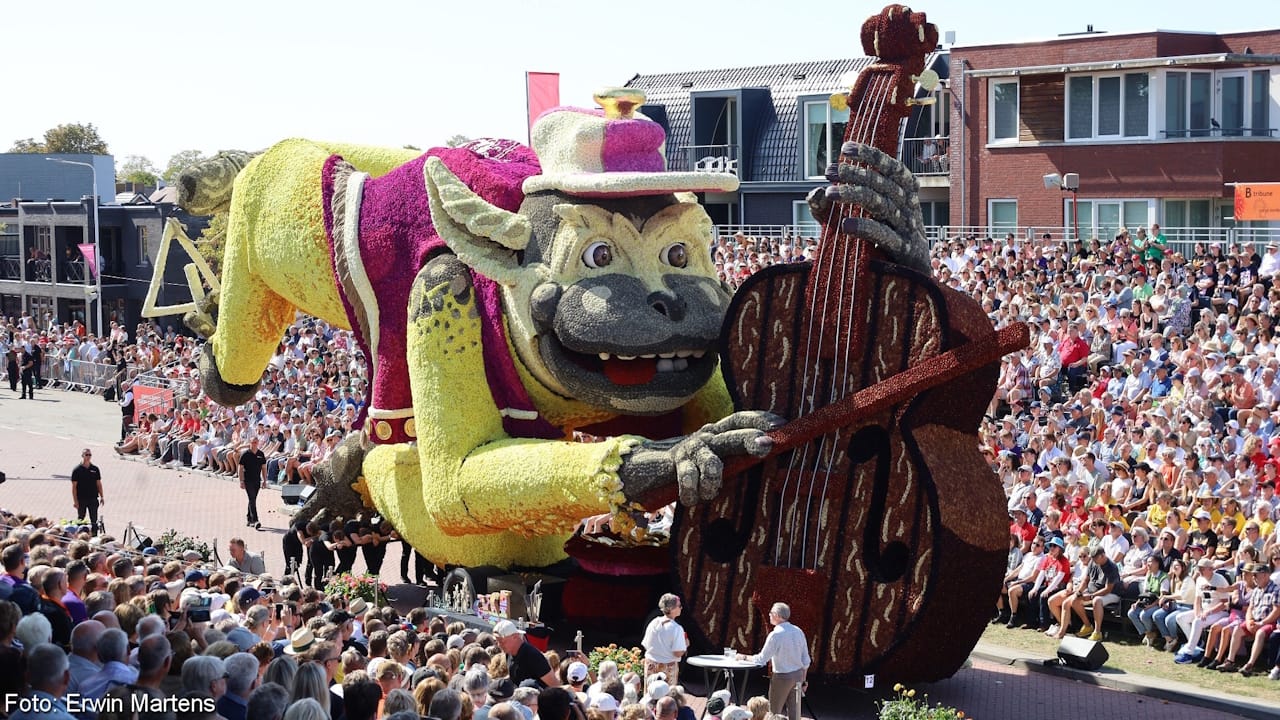 Flower parade float showing a yellow monkey playing a brown violin made entirely of Dahlias.