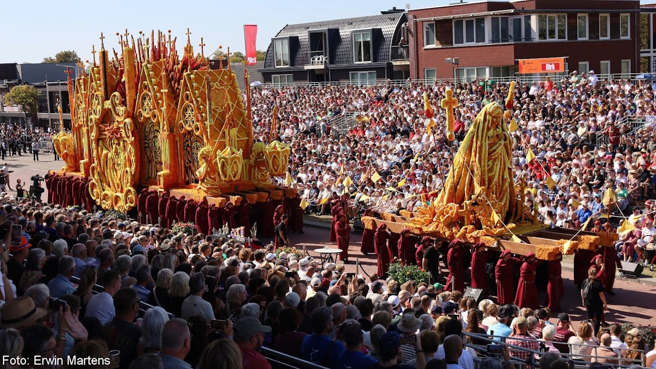 Incredible parade float made entirely of Dahlias showing a female saint and church all in orange and yellow.