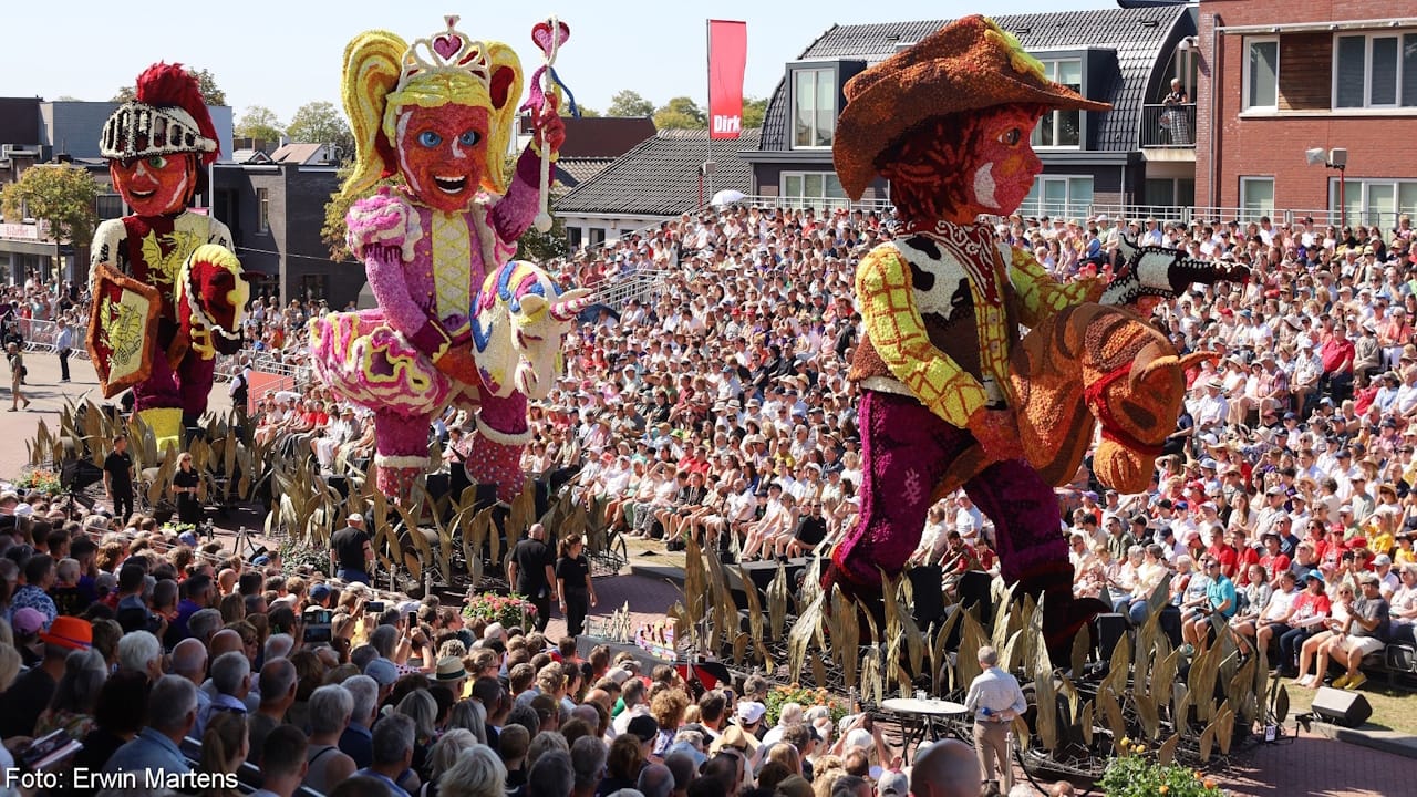 Very colorful flower parade float showing three children riding stick horses: a cowboy, a ballerina and a Roman soldier